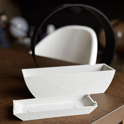 3D-printed stone-textured self-watering flower pot.