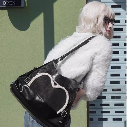 Stylish black tote backpack with heart embellishment - can be worn on one shoulder or as a backpack.